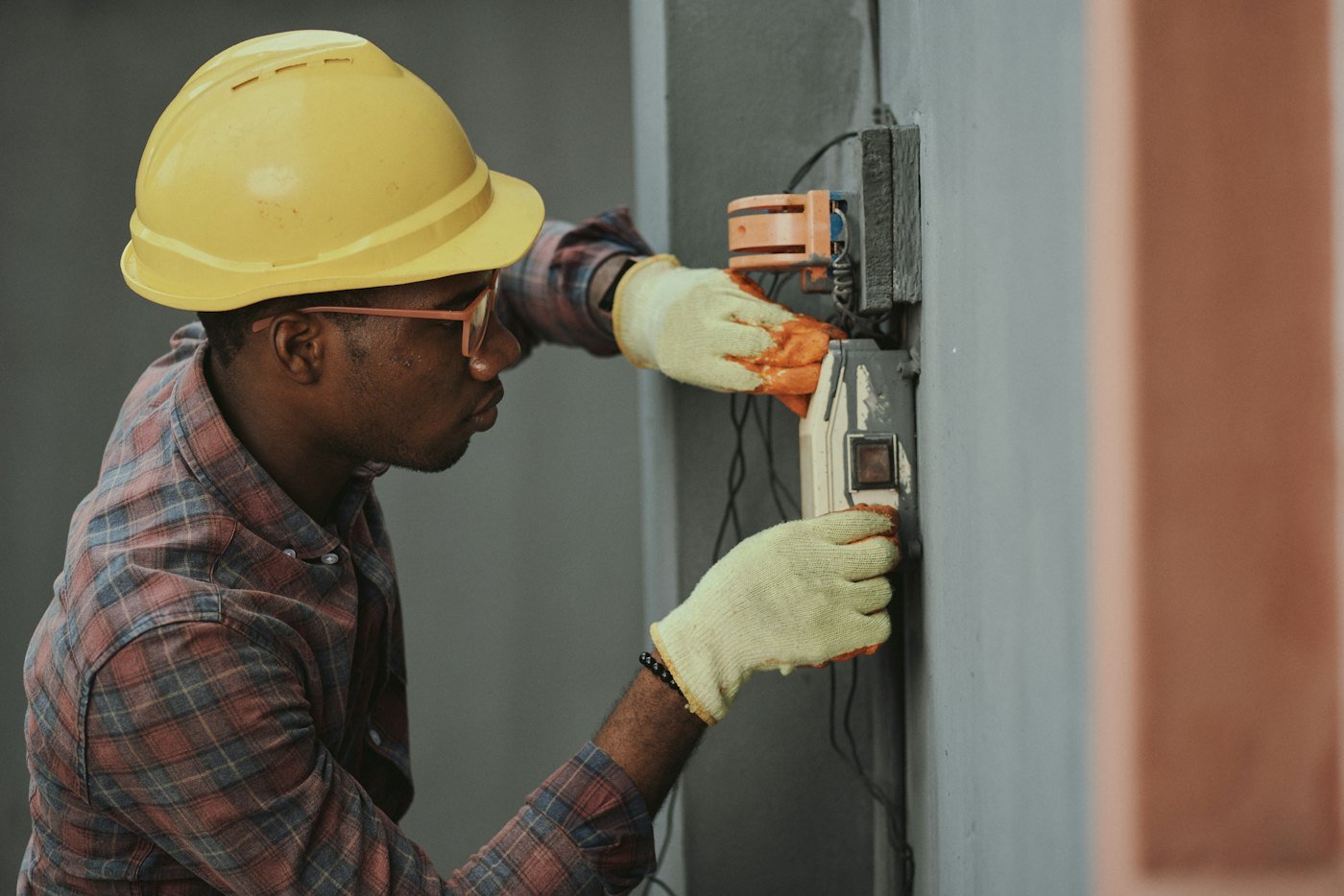 Électricien en casque de chantier intervenant sur un tableau électrique